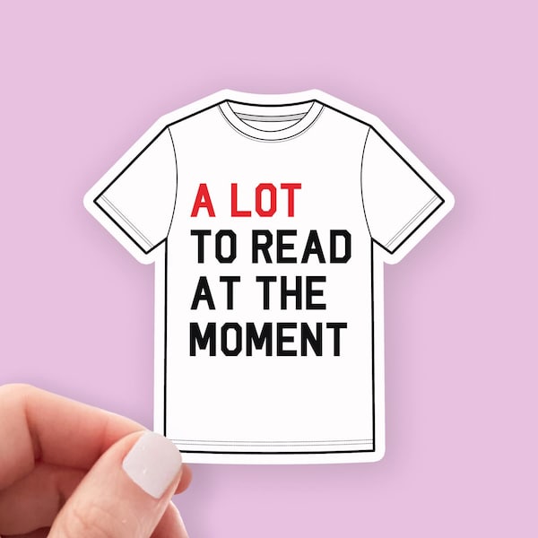 Peut inclure: Un t-shirt blanc avec du texte noir qui dit "A LOT TO READ AT THE MOMENT". Le mot "LOT" est en rouge.