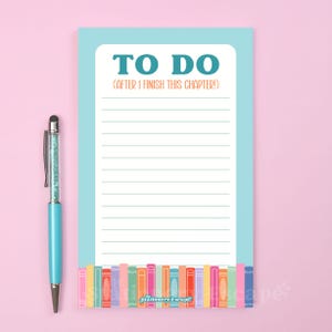 Könnte beinhalten: Ein hellblaues Notizblock mit den Worten "TO DO" und "(AFTER I FINISH THIS CHAPTER!)" aufgedruckt. Der Notizblock hat linierte Seiten und ein farbenfrohes Bücherregal-Design am unteren Rand. Ein passender hellblauer Stift mit silberner Spitze befindet sich links.
