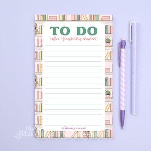 May include: A pastel pink To Do list notepad with a bookshelf border and the text "TO DO (after I finish this chapter!)". Two purple pens are next to the notepad. The notepad has lined pages.