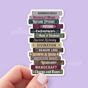 May include: A die-cut sticker featuring a vertical stack of twelve books with various colored spines. The titles printed on the spines are Advanced Spells, History of Magic, Arcane Studies, Potions, Enchantments, Book of Shadows, Ancient Alchemy, Divination, Dragon Lore, Secrets & Sigils, Protective Wards, Herbology, Wandcraft, and Charms and Runes.