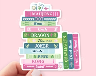 May include: A sticker featuring a stack of colorful books with titles related to Mahjong. The books are in various colors, including pink, green, and blue, with titles like "Mahjong," "Dragon," and "Joker."