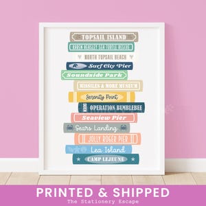 May include: A framed print featuring a stack of colorful, rectangular signs with various names like "Topsail Island" and "Surf City Pier." The print includes the text "Printed & Shipped" at the bottom.