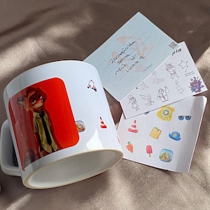 May include: A white ceramic mug featuring a graphic of a fox character in a green shirt and tie against a red background. Beside the mug are two white cards with various small stickers, including a police badge, traffic cones, and carrots.