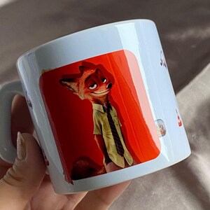 May include: A white ceramic mug featuring a printed graphic of a cartoon fox character with orange fur, wearing a light green short-sleeved button-down shirt and a dark striped tie, set against a vibrant red background on the side of the mug.