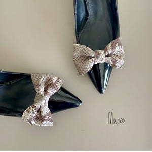 以下が含まれることがあります： 2足のスネーク柄のリボンが付いた黒のポインテッドトゥシューズ。画像の右下に「Ma-oo」の文字が書かれている。