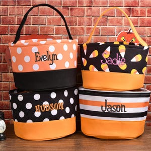 May include: Four personalized Halloween treat bags. One orange bag with white polka dots and the name "Evelyn". A black bag with white polka dots and the name "Hudson". A black bag with candy corn and the name "Sadie". A bag with black and white stripes and the name "Jason".
