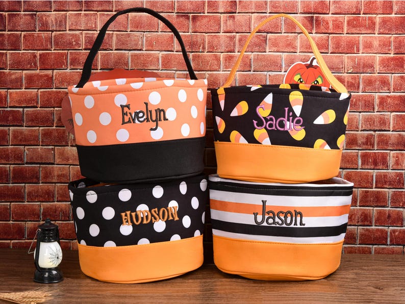 May include: Four personalized Halloween treat bags. One orange bag with white polka dots and the name "Evelyn". A black bag with white polka dots and the name "Hudson". A black bag with candy corn and the name "Sadie". A bag with black and white stripes and the name "Jason".