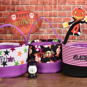 May include: Three Halloween-themed treat bags with purple accents. One bag is white with star graphics and the name "Ethan". Another is black with candy graphics and the name "Stella". The third is striped with the name "Claire".