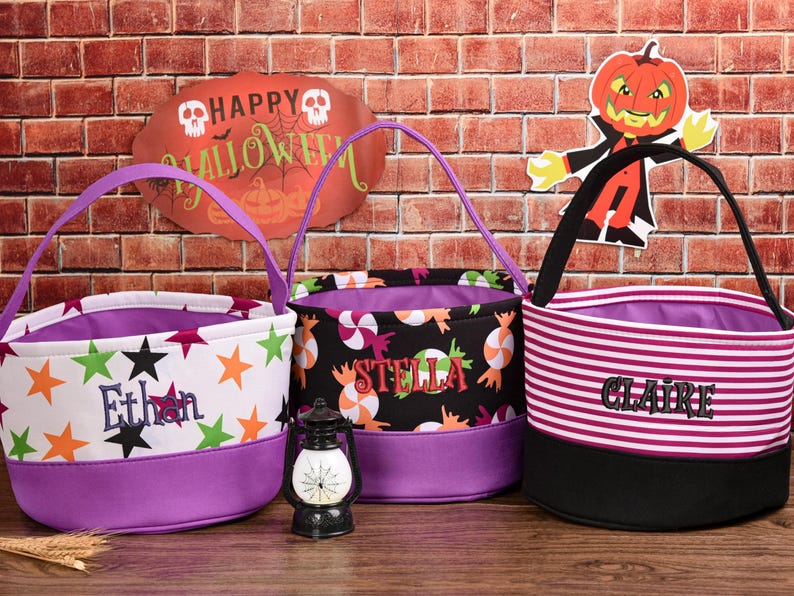 May include: Three Halloween-themed treat bags with purple accents. One bag is white with star graphics and the name "Ethan". Another is black with candy graphics and the name "Stella". The third is striped with the name "Claire".