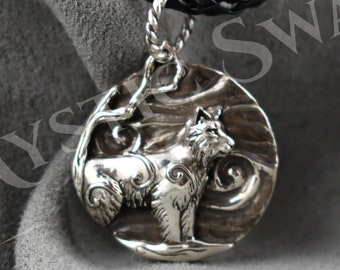 May include: Silver pendant necklace featuring a wolf howling at the moon with a tree branch in the background. The pendant is on a black braided cord.