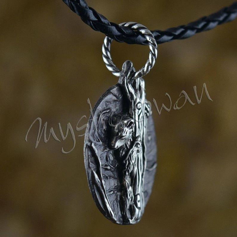 Puede incluir: Un collar con un colgante de plata con un dise&ntilde;o detallado de una ardilla trepando a un &aacute;rbol. El colgante tiene forma ovalada y una superficie texturizada.