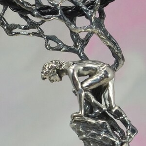 May include: A silver sculpture of a person climbing a tree. The sculpture is detailed and intricate, with the person's features and the tree's branches clearly defined.