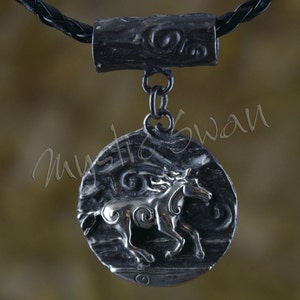 Puede incluir: Un collar con un colgante de plata en un cord&oacute;n de cuero negro. El colgante presenta un dise&ntilde;o detallado de un caballo corriendo a trav&eacute;s de un patr&oacute;n de remolino.