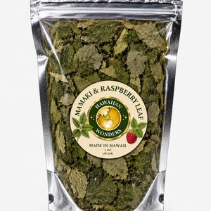 May include: A silver foil stand-up pouch filled with dried green Mamaki and raspberry leaves. The circular label features the text Hawaiian Wonders, Mamaki & Raspberry Leaf, Made in Hawaii, and the weight of 1 oz (28 gm) with a raspberry graphic.
