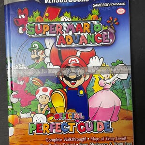 May include: A colorful guide book for the Game Boy Advance video game Super Mario Advance. The cover features Mario, Luigi, Peach, and Yoshi in a jungle setting. The book includes a complete walkthrough, maps of every level, boss-busting tactics, and strategies for the bonus Mario Bros. game.