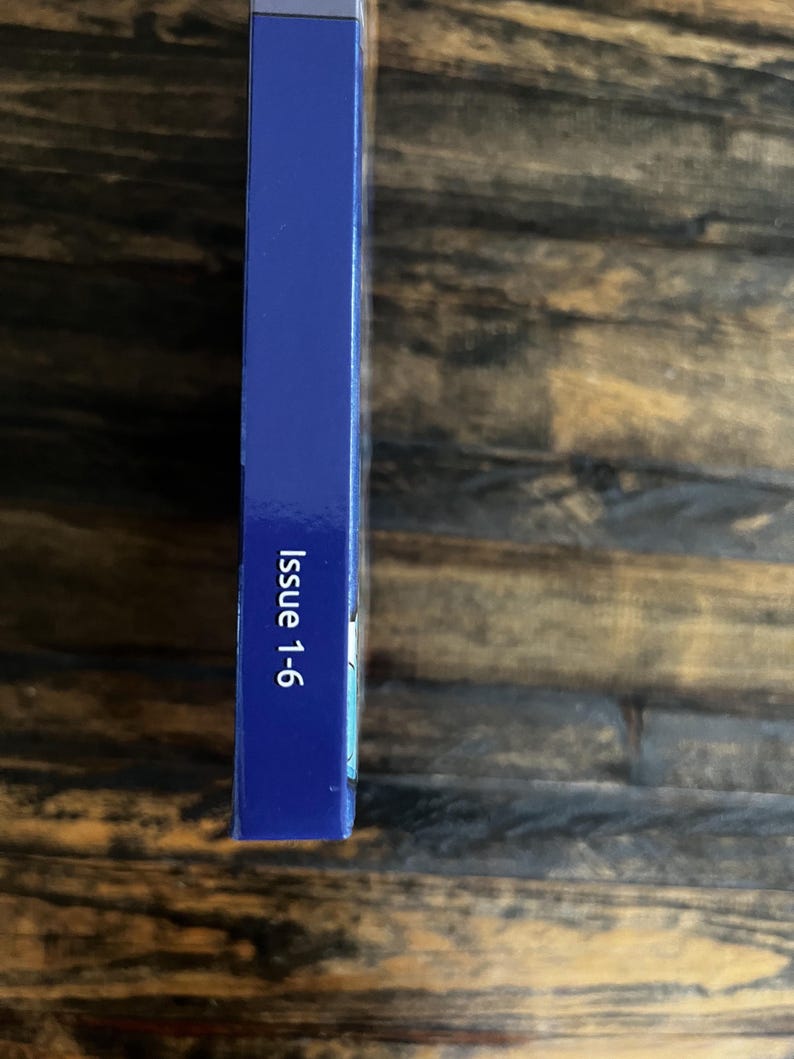 May include: A dark blue rectangular object with the text "Issue 1-6" printed in white. The object is positioned vertically against a wooden background. The object's surface is smooth.