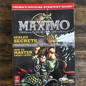 May include: A Prima's Official Strategy Guide for the video game Maximo: Ghosts to Glory. The cover features the game's title in a silver font, a muscular character, and the text "Sealed Secrets" and "How to Master Every Level."