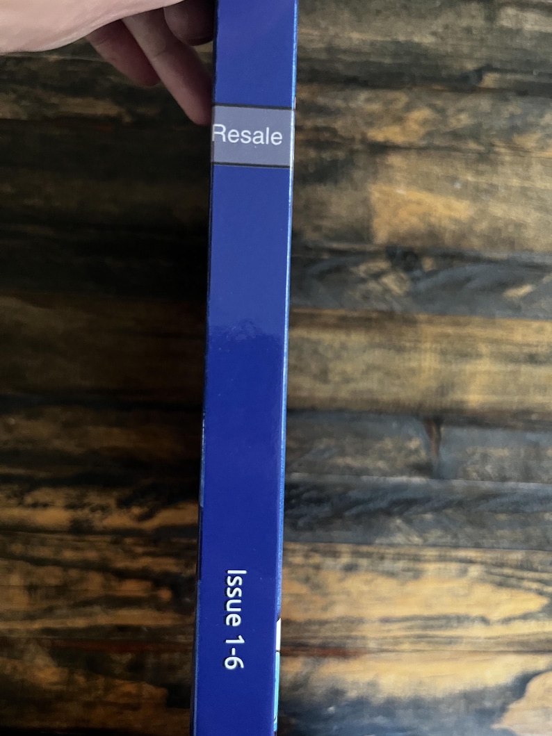 May include: A blue book spine with the word "Resale" in white text on a white label. The text "Issue 1-6" is printed in white on the lower portion of the spine. The background is a wooden surface.
