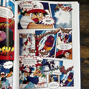 May include: A comic book page with vibrant panels from Pok&eacute;mon. The illustrations show characters in action, with speech bubbles displaying phrases such as "POK&Eacute; BALL!" and "GO!" The artwork has a dynamic, action-oriented style.
