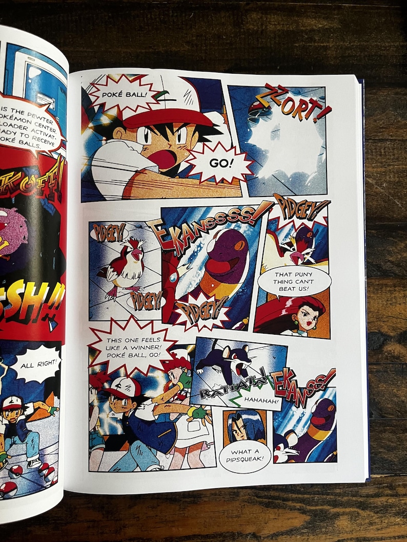 May include: A comic book page with vibrant panels from Pok&eacute;mon. The illustrations show characters in action, with speech bubbles displaying phrases such as "POK&Eacute; BALL!" and "GO!" The artwork has a dynamic, action-oriented style.