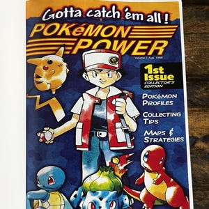 May include: A vintage Pok&eacute;mon Power magazine cover. The cover features the text "Gotta catch 'em all!" and "Pok&eacute;mon Power." The cover art includes the main character and several Pok&eacute;mon characters, including Pikachu, Squirtle, Bulbasaur, and Charmander. The magazine is a 1st Issue Collector's Edition.