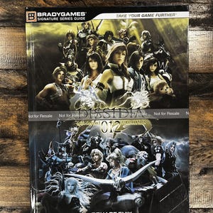 May include: A BradyGames Signature Series Guide for Dissidia 012, featuring character illustrations. The cover includes the text "TAKE YOUR GAME FURTHER" and "SQUARE ENIX". The guide is marked "Not for Resale".
