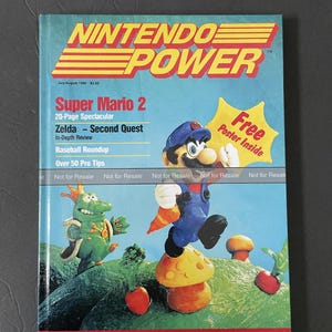 May include: A magazine cover for Nintendo Power, featuring Super Mario 2 on the front cover. The cover features a claymation-style image of Mario standing on a mushroom, with a green, reptilian creature in the background. The text on the cover reads "Super Mario 2", "20-Page Spectacular", "Zelda - Second Quest", "In-Depth Review", "Baseball Roundup", "Over 50 Pro Tips", "Free Poster Inside", and "Nintendo Power".
