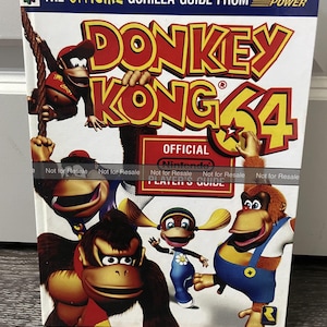 May include: A colorful cover for the official Donkey Kong 64 player's guide. The cover features Donkey Kong, Diddy Kong, Tiny Kong, and Lanky Kong. The cover is red, yellow, and blue with the title "Donkey Kong 64" in large, bold letters.