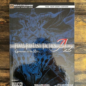 May include: A Final Fantasy Tactics strategy guide. The cover features a blue and black illustration with the game title and logo. The BradyGames Official Strategy Guide is for Nintendo DS.