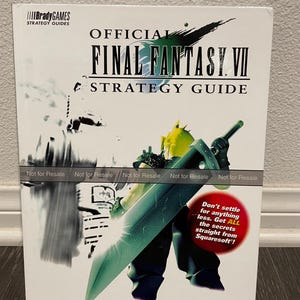 May include: A white cover for the Final Fantasy VII strategy guide. The cover features a character from the game, Cloud Strife, holding a large sword. The text on the cover reads "Official Final Fantasy VII Strategy Guide" and "Don't settle for anything less. Get all the secrets straight from Squaresoft!"