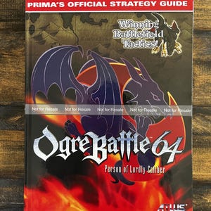 May include: A Prima's Official Strategy Guide for Ogre Battle 64. The cover features a dragon illustration with a red and orange background. The text "Winning Battlefield Tactics!" is also visible.