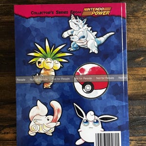 May include: A book cover with Pok&eacute;mon characters on a blue background. The cover has the text "COLLECTOR'S SERIES FROM NINTENDO POWER." The Pok&eacute;mon include Exeggutor, Wigglytuff, and a Pok&eacute; Ball. The cover has a barcode.