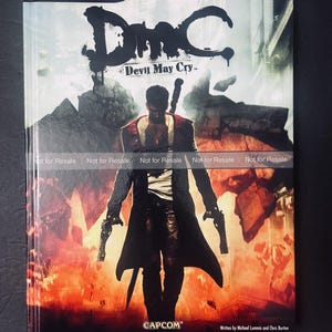 May include: A BradyGames Signature Series Guide for DmC Devil May Cry. The cover features a character illustration with guns and a sword against a fiery background. The game title is in large, stylized letters.