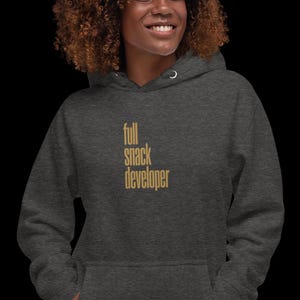 Op de afbeelding: Donkergrijze hoodie met de tekst "full snack developer" in goud. De hoodie heeft een capuchon met trekkoord en een voorzak. De tekst is verticaal uitgelijnd.