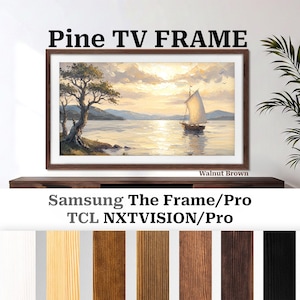 Puede incluir: Un marco de TV de pino marrón nogal con una pintura de paisaje de un velero en el agua. El marco se muestra en un mueble marrón oscuro. Se ve el texto "Pine TV FRAME" y "Walnut Brown".