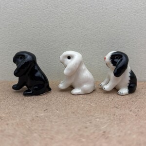 May include: Three ceramic rabbit figurines. One is black, one is white, and one is black and white.