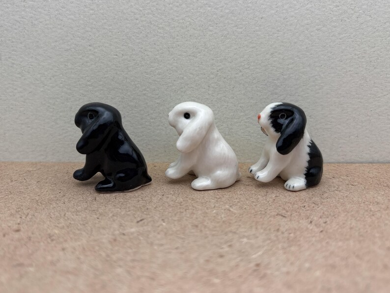 May include: Three ceramic rabbit figurines. One is black, one is white, and one is black and white.