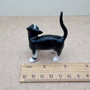 K&ouml;nnte beinhalten: Kleine Katze-Figur aus Keramik in Schwarz und Wei&szlig;. Die Katze steht mit erhobenem Schwanz und zur&uuml;ckgeneigtem Kopf. Die Figur ist etwa 5 cm lang.