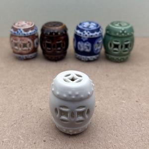 May include: Six small ceramic decorative items shaped like traditional Chinese pagodas. The pagodas are in various colors, including white, brown, blue, and green. Each pagoda has a unique design with intricate details.