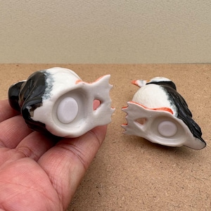 May include: Two ceramic salt and pepper shakers shaped like puffins. The puffins are black and white with orange beaks. The shakers are upside down, showing the white ceramic bottoms with a hole in the center.