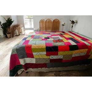 May include: A large patchwork quilt with a variety of colors and patterns, including red, green, yellow, blue, and white. The quilt is made of different fabrics and textures, and it has a hand-stitched look.