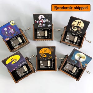 May include: Wooden music boxes with various illustrations from "The Nightmare Before Christmas." Each box features a different scene, including Jack and Sally, and the text "The Nightmare Before Christmas." The boxes have a hand crank.