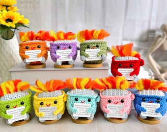 May include: Ten crocheted plush toys shaped like fire with different colored bodies and flames. Each toy holds a sign that reads "Emotional Support Dumpster Fire It's fine I'm fine Everything is fine!"