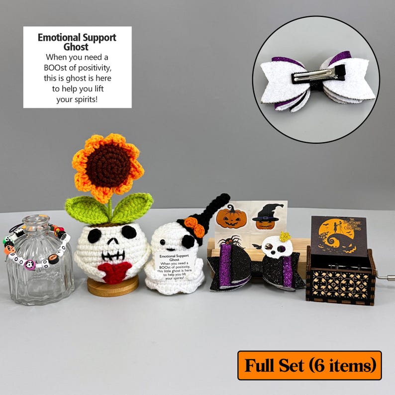 May include: A collection of Halloween-themed items, including a crochet sunflower, ghost figures, a bow, and a music box. The items are white, orange, black, and purple. The text on the image says "Emotional Support Ghost".