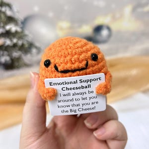 May include: Orange crocheted cheeseball holding a card that says "Emotional Support Cheeseball I will always be around to let you know that you are the Big Cheese!"