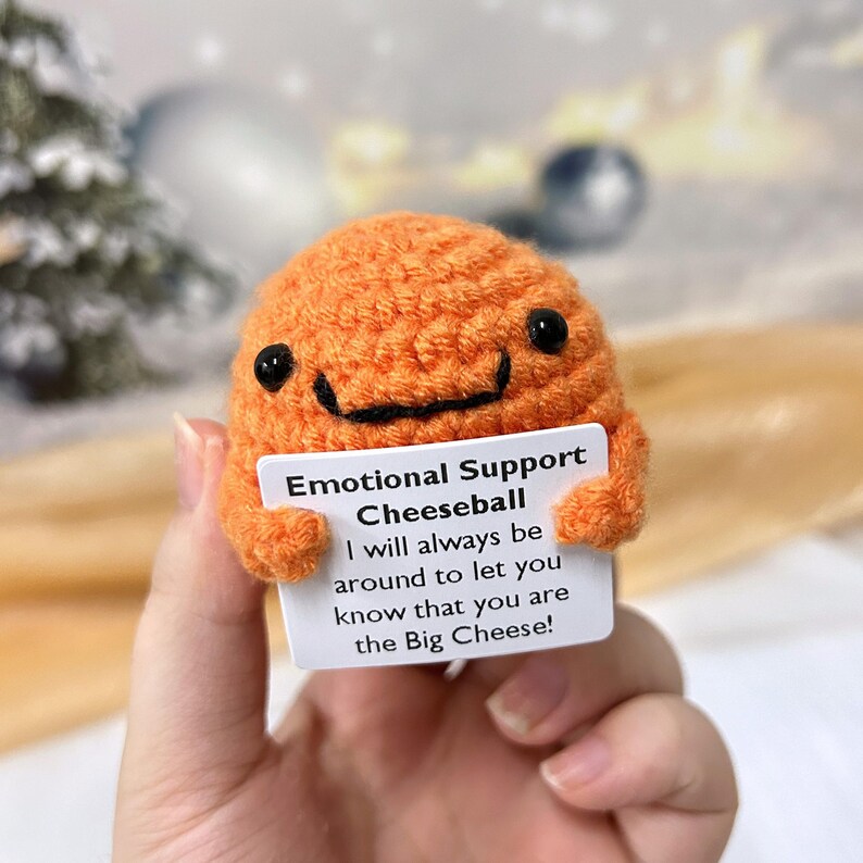 May include: Orange crocheted cheeseball holding a card that says "Emotional Support Cheeseball I will always be around to let you know that you are the Big Cheese!"