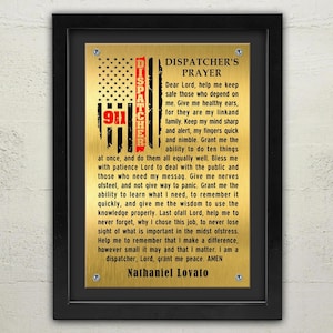 Peut inclure: Une plaque dorée avec un cadre noir et un motif de drapeau américain rouge, blanc et bleu. La plaque présente une prière pour les répartiteurs, avec le texte "A Dispatcher's Prayer" et "Nathaniel Lovato" en bas.