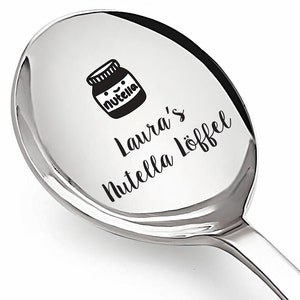 Könnte beinhalten: Ein silberner Löffel mit einer schwarz-weißen Illustration eines Nutella-Glases und dem Text "Laura's Nutella Löffel" auf der Vorderseite.