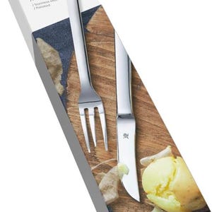 Op de afbeelding: Een zilveren set voor het schillen van aardappelen, bestaande uit een mes en een vork, in een doos met de merknaam "WMF Nuova". De doos heeft de tekst "Pellkartoffel-Set 2-teilig Potato peeling set 2-piece /Edelstahl Rostfrei Poliert /Stainless steel Polished".