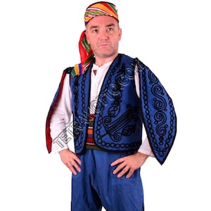 Puede incluir: Un traje tradicional con un chaleco azul con bordados negros, una camisa blanca y pantalones azules. El atuendo incluye un tocado colorido. El chaleco tiene un patrón decorativo.